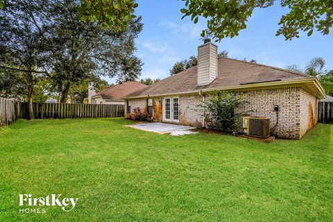 a backyard with a fence and a brick house with a lawn