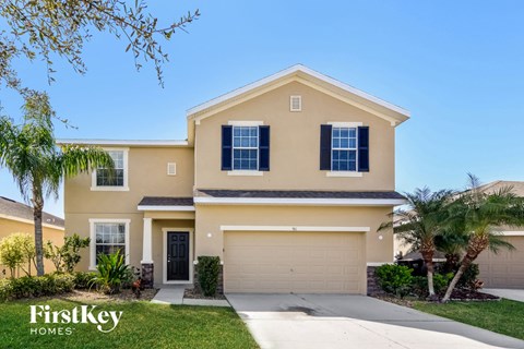 a beige house with a garage door and palm trees