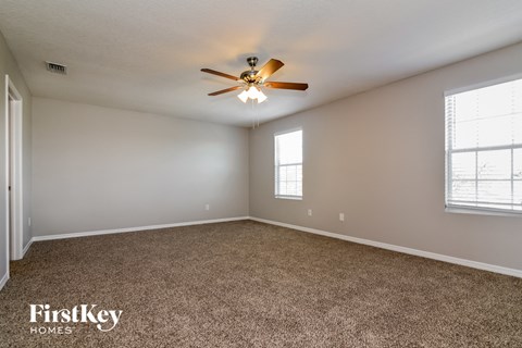the master bedroom has a carpeted floor and a ceiling fan