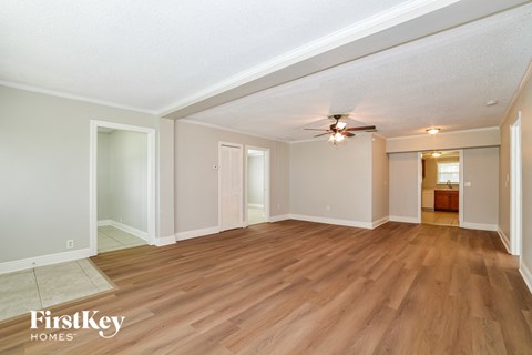 A spacious room with wooden flooring and a ceiling fan.