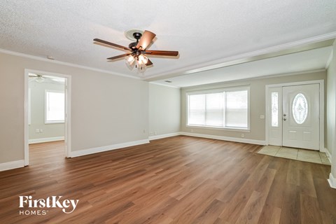 A room with a ceiling fan and wooden floors.