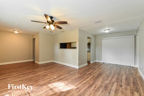 the living room and dining room with wood flooring and a ceiling fan