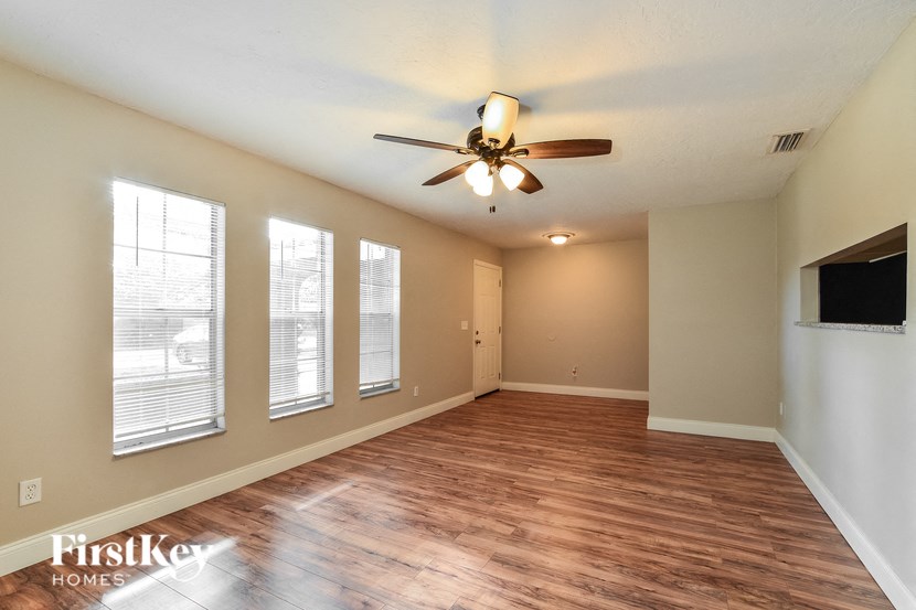 an empty living room with wood floors and a ceiling fan