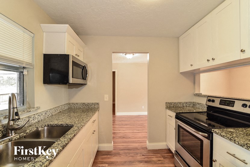 a kitchen with granite counter tops and black appliances and white cabinets