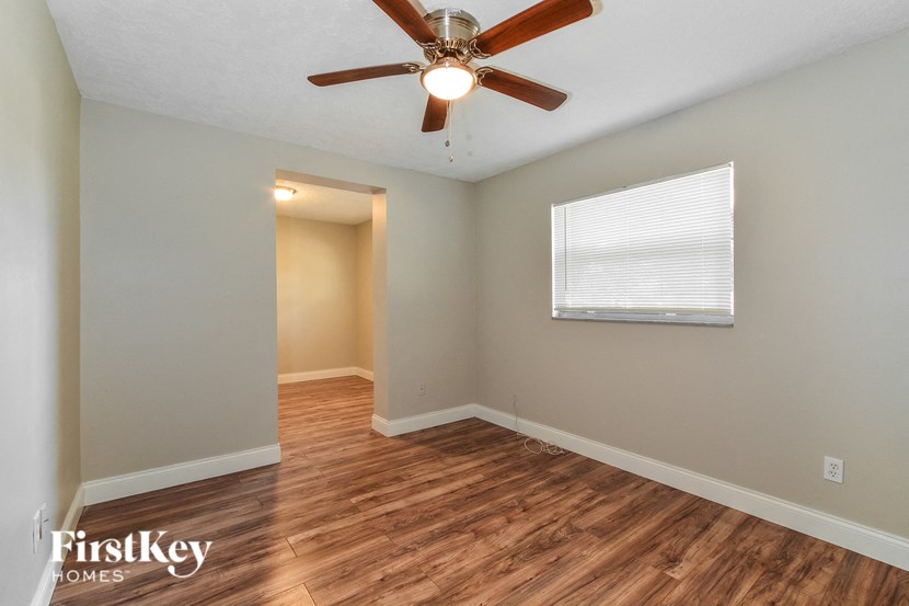 the living room and dining room with hardwood floors and a ceiling fan