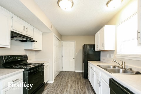 a white kitchen with black appliances and white cabinets
