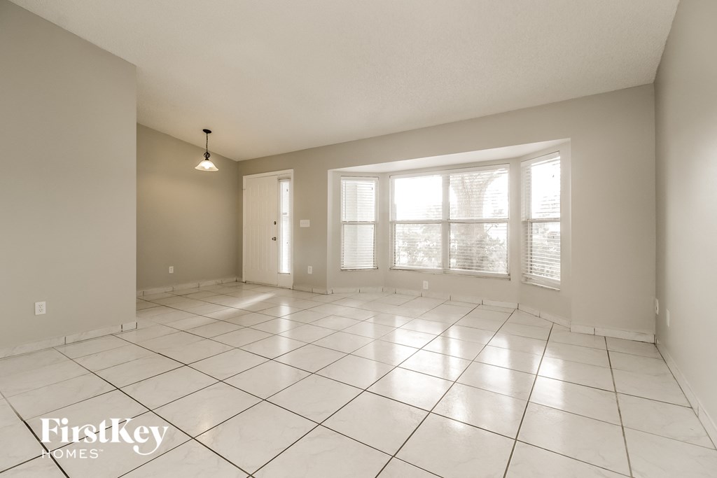A spacious room with white tiled flooring and a large window.