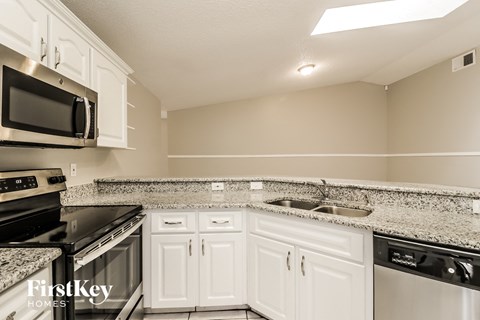 A kitchen with white cabinets and black appliances.