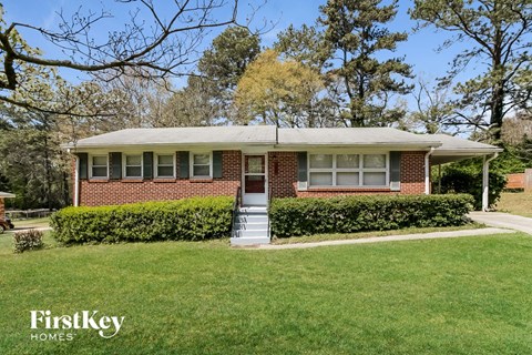 the front of a brick house with a lawn and stairs