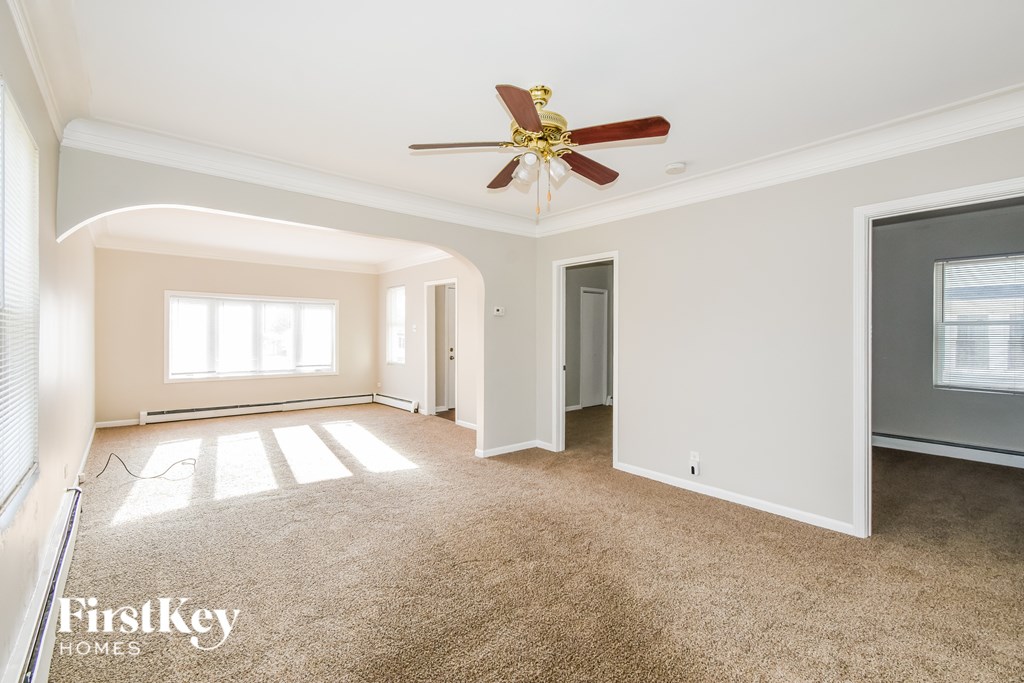 A spacious room with a ceiling fan and a large window.
