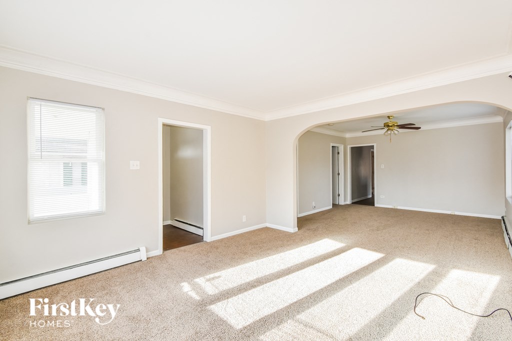 A spacious room with a fan and carpeted floor.