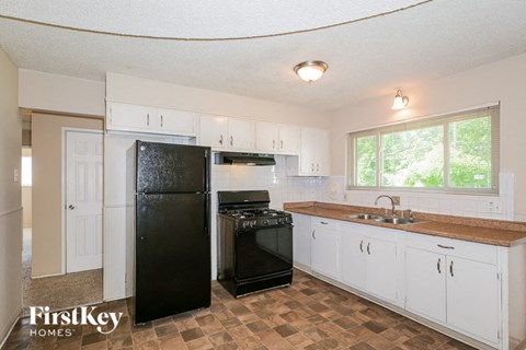 a kitchen with white cabinets and a black refrigerator