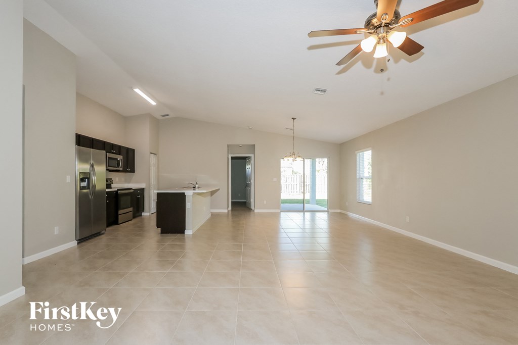 an empty living room and kitchen with a ceiling fan
