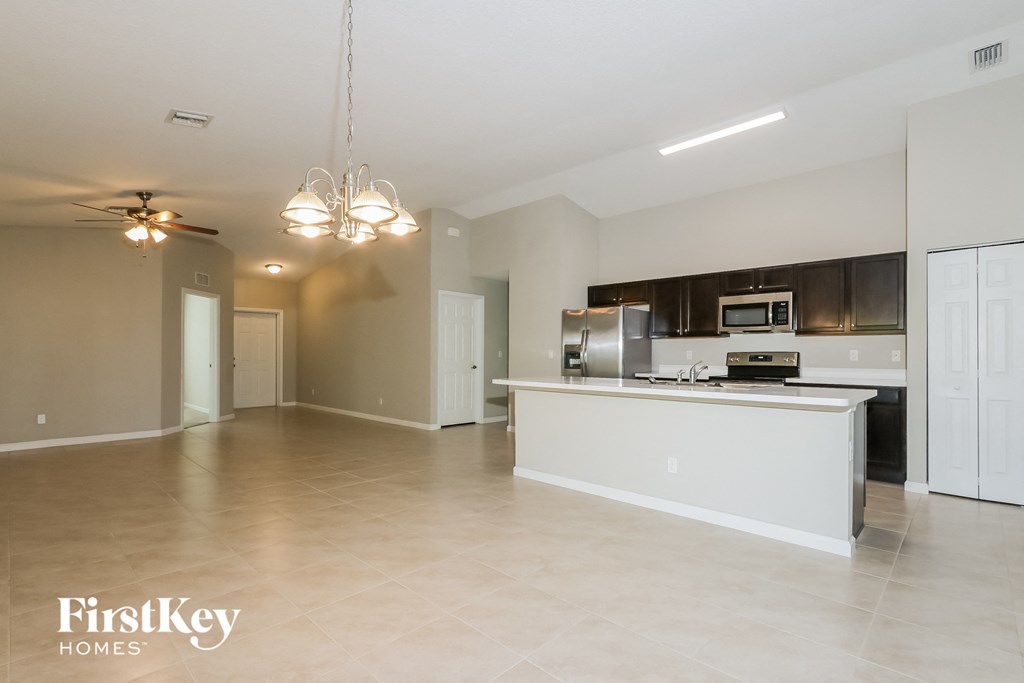 an empty living room and kitchen with a counter top and a refrigerator