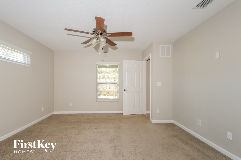 a living room with a ceiling fan and a carpet