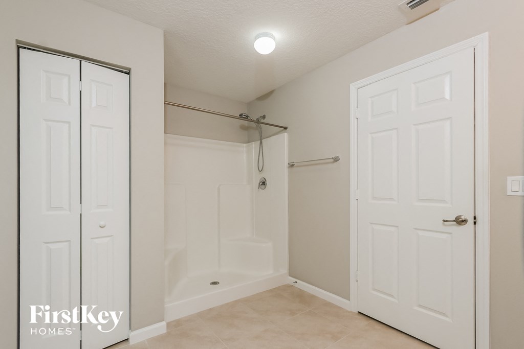 a bathroom with a shower and a closet and white doors