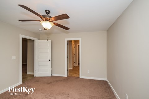 a bedroom with a ceiling fan and a door to a hallway