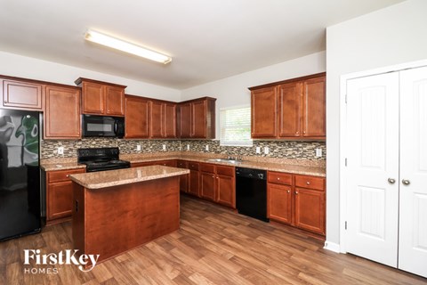 A kitchen with wooden cabinets and a black fridge.