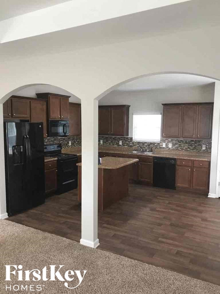 A kitchen with a black fridge and brown cabinets.