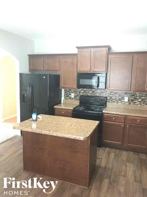 A kitchen with wooden cabinets and a black stove top oven.