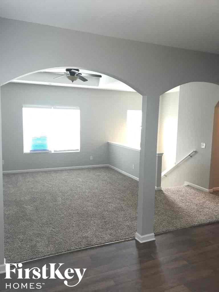 A room with a carpeted floor and a fan on the ceiling.