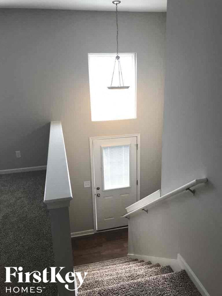 A stairway with a carpeted floor and a light hanging from the ceiling.