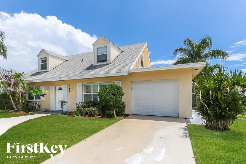 A house with a white garage door and a blue sky in the background.