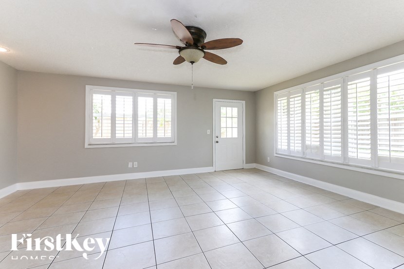 A spacious room with a ceiling fan and tiled flooring.
