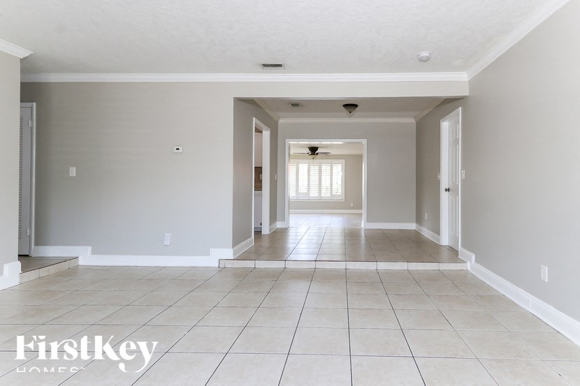 A spacious room with tiled flooring and a ceiling fan.