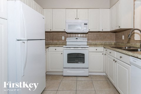 A kitchen with white appliances and cabinets.