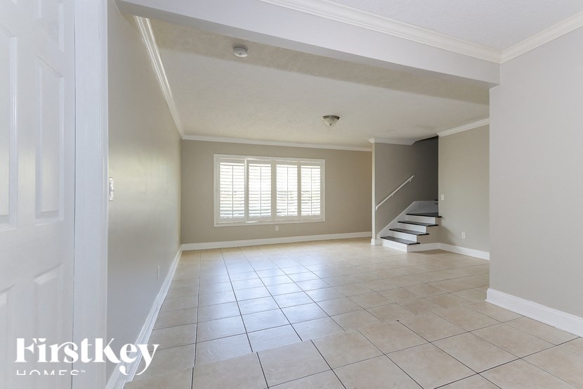 A spacious room with a staircase and a window with blinds.