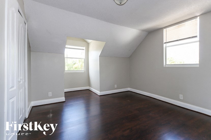 A room with wooden floors and two windows.
