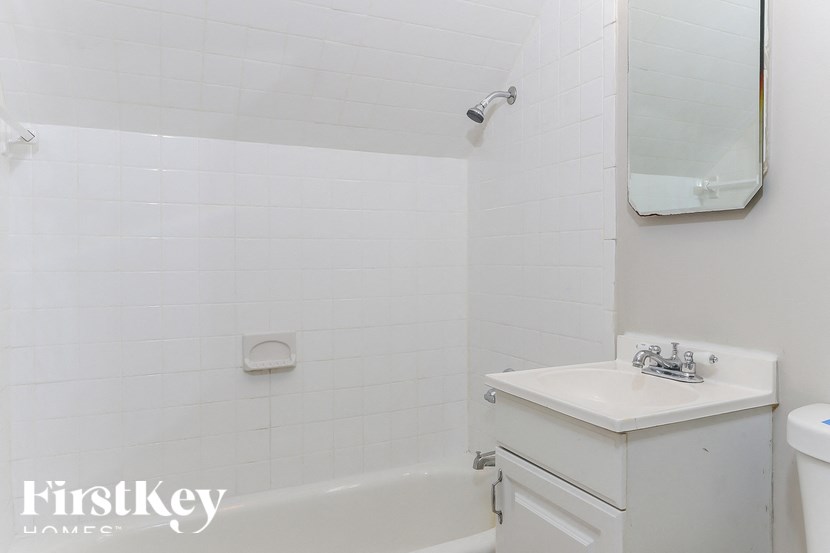 A white bathroom with a sink and a mirror.
