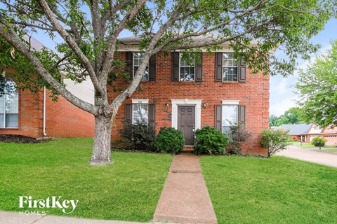 a brick house with a tree in front of it