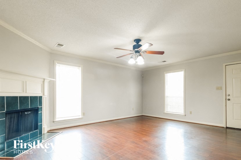 an empty living room with a ceiling fan and a fireplace