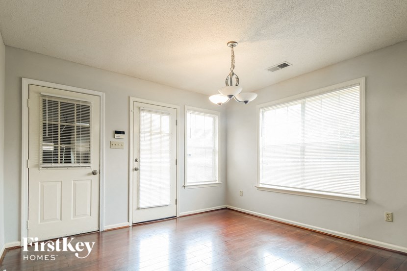an empty living room with a white door and two windows