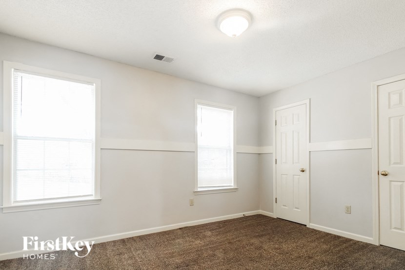a bedroom with white walls and two windows and a carpet