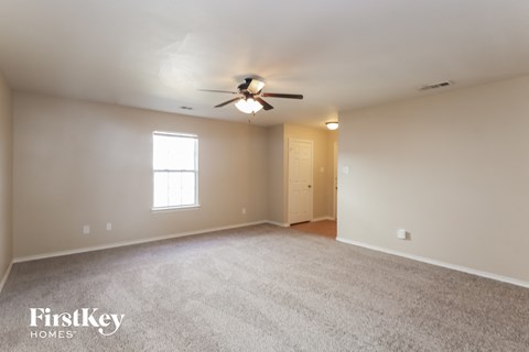 a living room with a ceiling fan and a white carpet