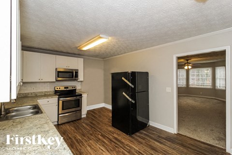 A kitchen with a black fridge and stove top oven.