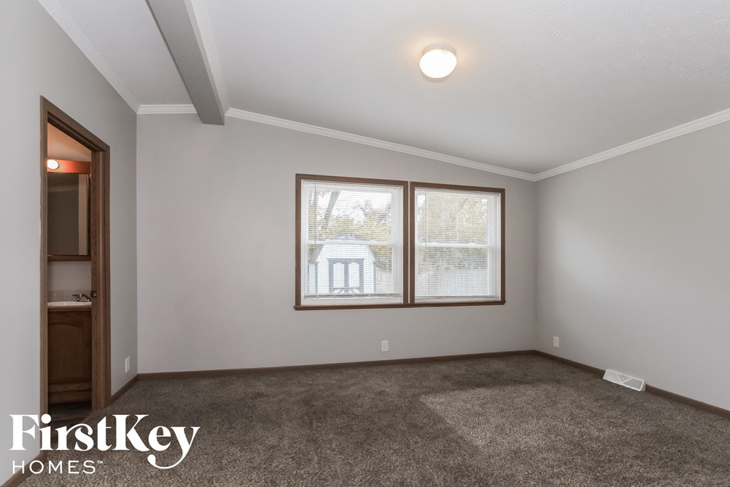 the living room of a house with carpet and two windows