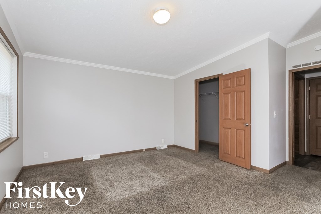 a bedroom with a carpeted floor and a door to a closet