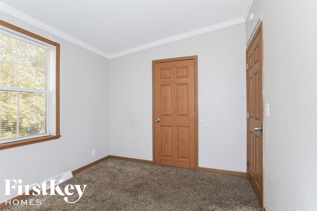 a bedroom with white walls and a wooden door and a window