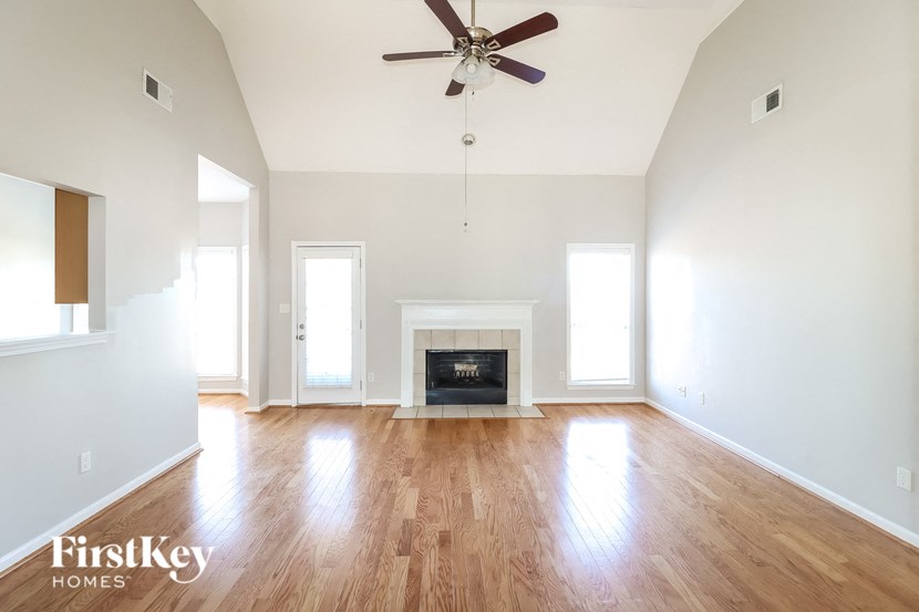 A spacious room with a fireplace and a ceiling fan.