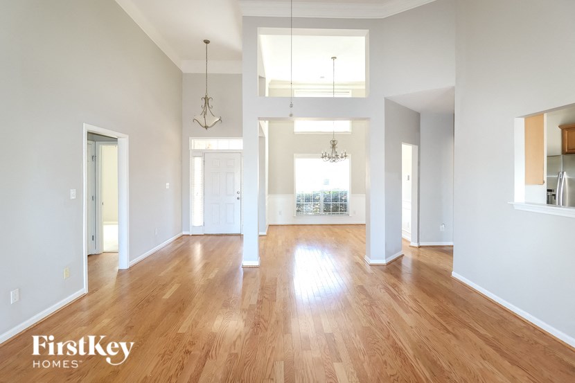 A spacious room with wooden floors and a chandelier hanging from the ceiling.