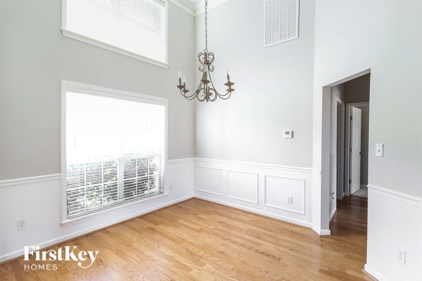 A room with a chandelier and a window with blinds.