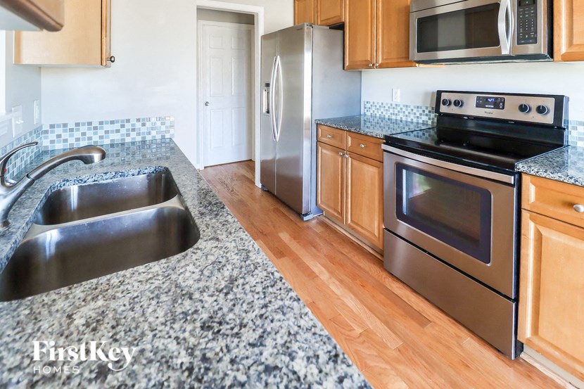 A kitchen with a stainless steel sink and a stove top oven.