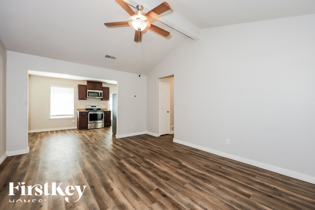 A spacious room with a ceiling fan and wooden flooring.
