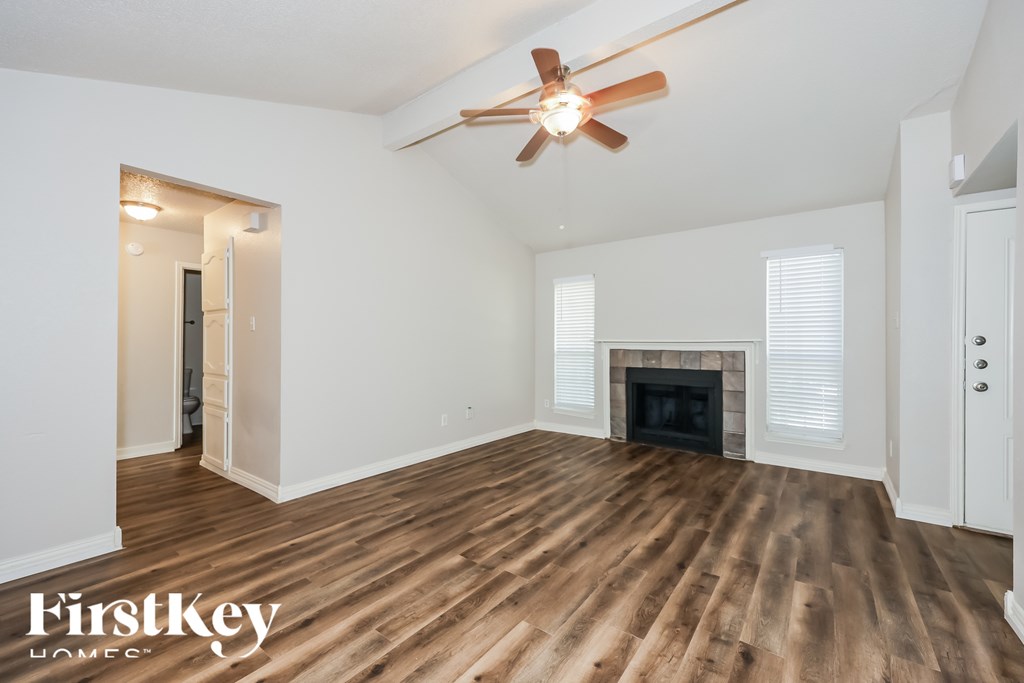 A spacious room with a fireplace and wooden flooring.