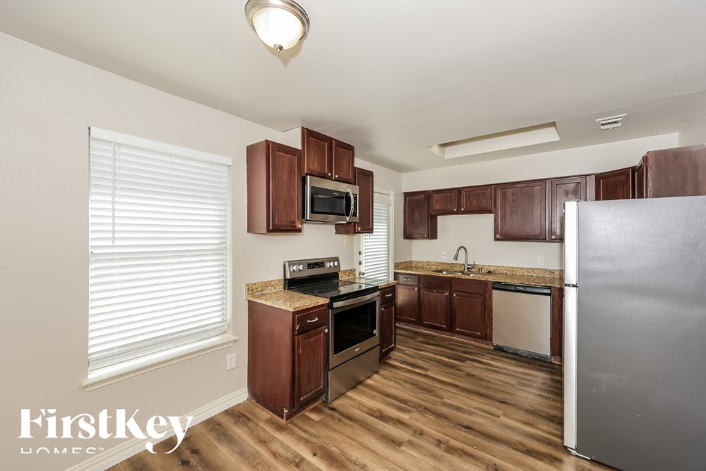 A kitchen with wooden cabinets and a stainless steel refrigerator.