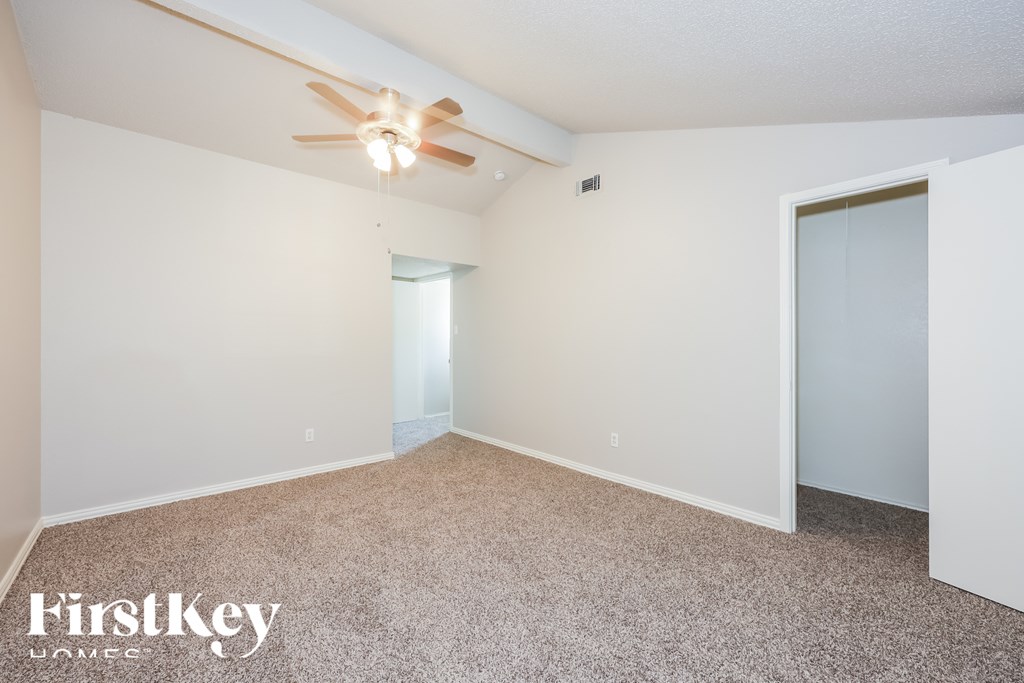 A room with a carpeted floor and a ceiling fan.